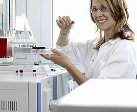 Eine Mitarbeiterin in einem Labor führt eine Wasseranalyse durch. Der Text hebt die hohe Qualität und Sorgfalt von MIDEWA bei der Wasseraufbereitung hervor.
