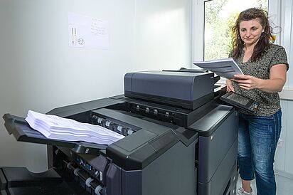Druckzentrum Midewa-Druckzentrum, Mitarbeiterin am Drucker
