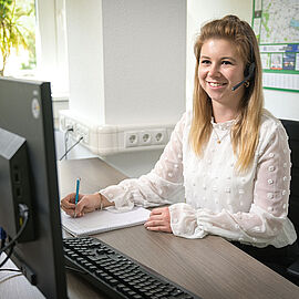 Midewa-Kundencenter / Mitarbeiterin am Computer führt über Headset ein Kundengespräch.